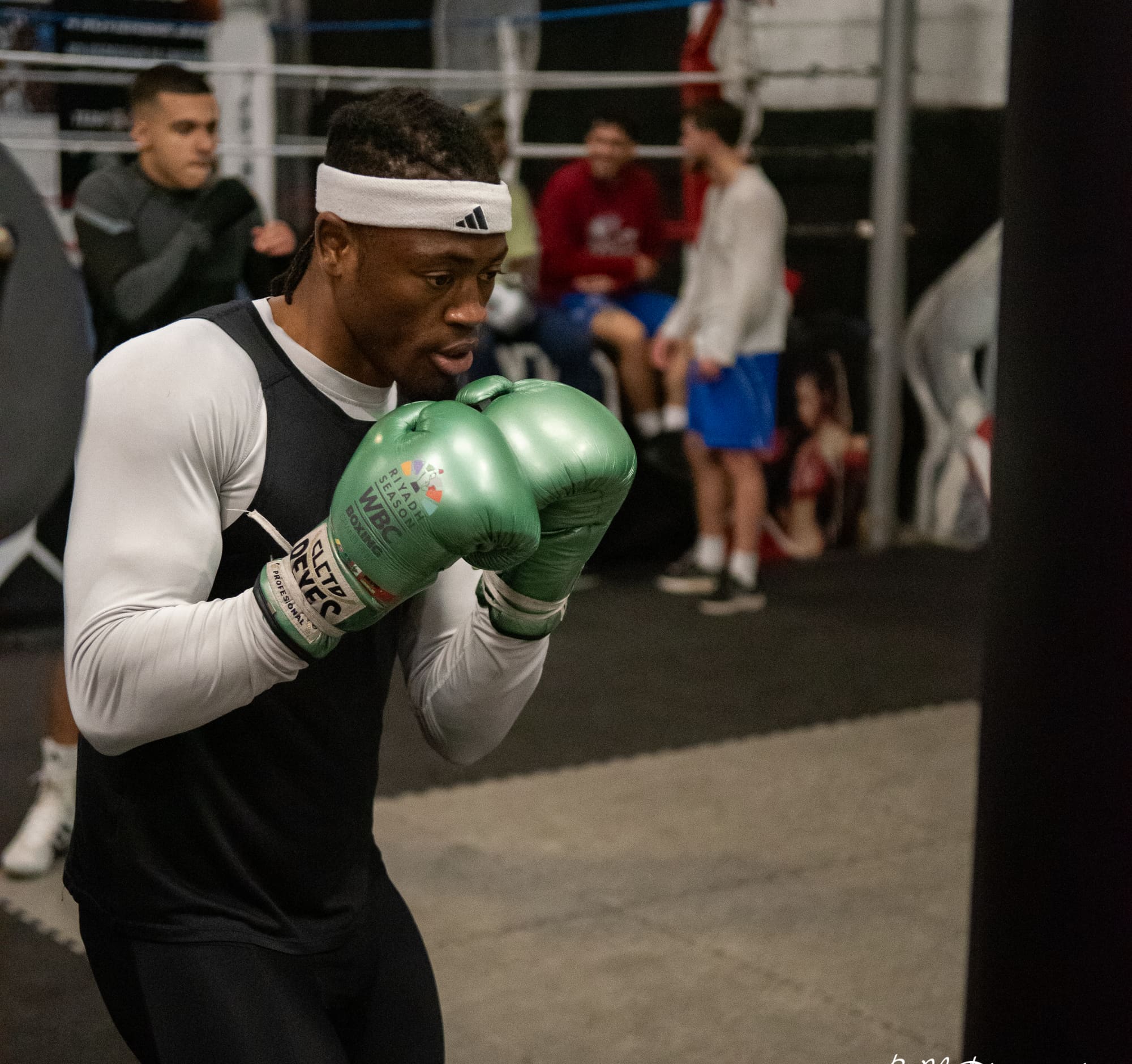 Un boxeur en garde haute pendant un exercice, gants verts.