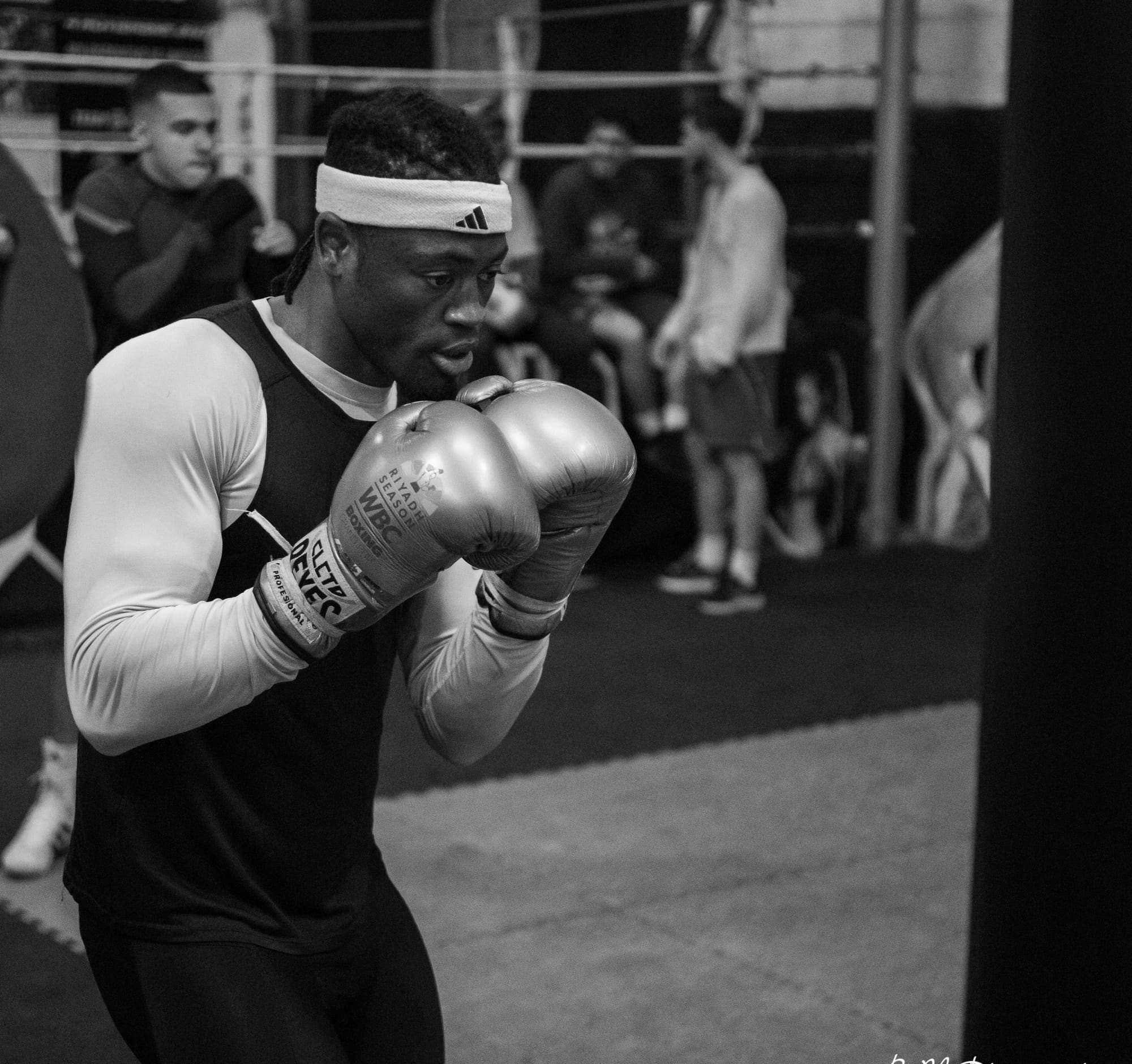 Un boxeur en garde haute pendant un exercice, en noir et blanc.