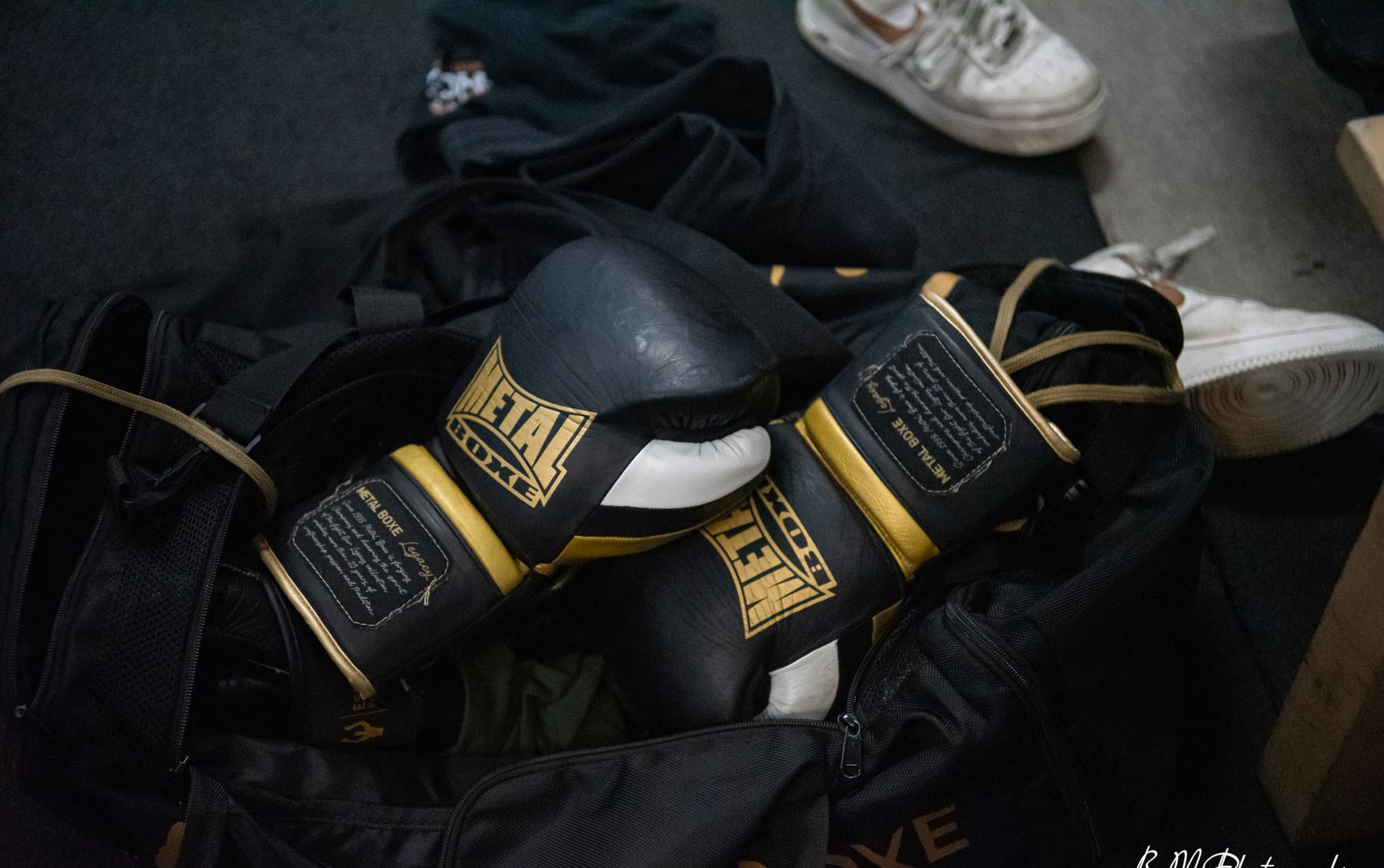 Gants de boxe et casque de protection posés sur un sac de sport dans le vestiaire du club.