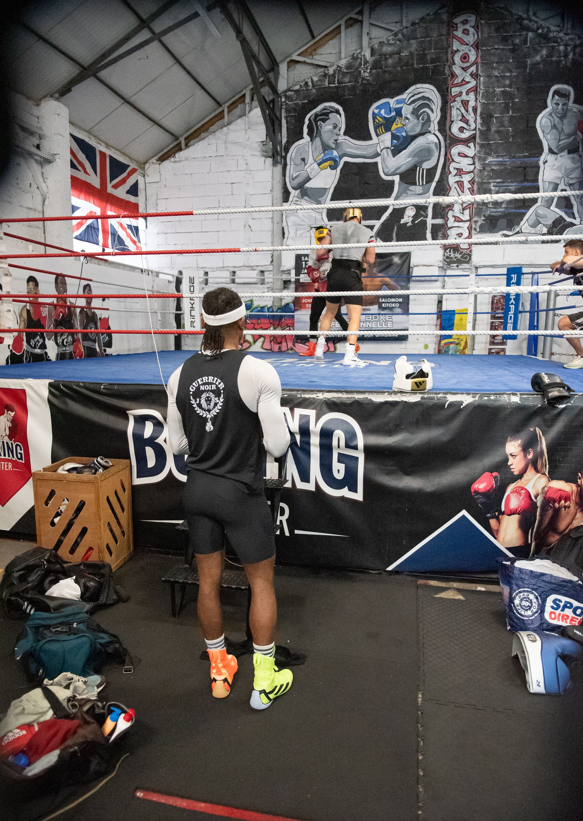 Un pratiquant de dos face au ring Boxing Center, dans la salle d'entraînement.